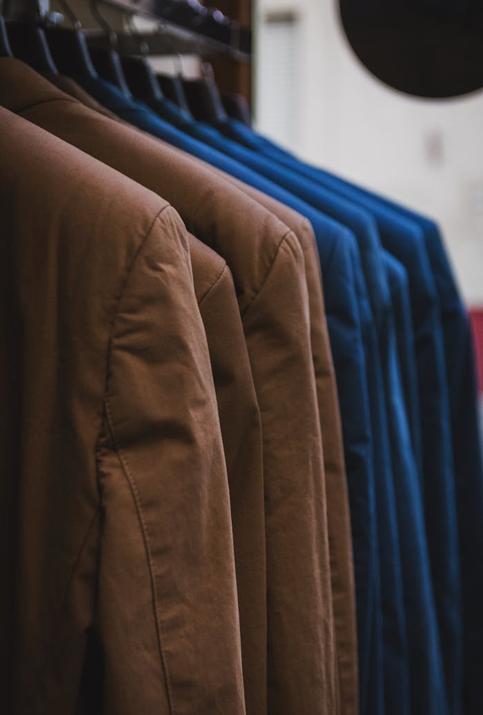 Showcase of neatly arranged brown and blue jackets on hangers, emphasizing fashion and style.